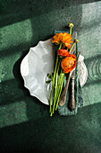 Draufsicht auf einen gedeckten Tisch mit Ranunkelblüten auf einem Betonhintergrund