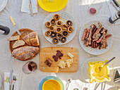 Flat lay of table served with plates of mushrooms hotdog grilled meat sauce slices of bread bottles and cups of drinks and fork spoons and knives