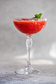 Cup of fresh Margarita cocktail with watermelon smoothie covered with mint leaves