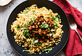 Top view of appetizing cuscus with beef and vegetable with tomatoes placed on gray table over blurred background