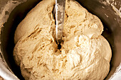 High angle view of fresh raw flour mixing in kneading machine for producing bread in industrial bakehouse