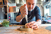 Crop focused chef using pastry bag to decorate tasty dessert on plate behind blurred kitchen background in restaurant at Zermatt Switzerland