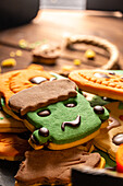 Focus of tasty Halloween cookies on plate placed on wooden table near rope