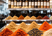 Colorful assorted traditional Moroccan spices placed on stall in market over blur street with people