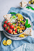 From above of delicious healthy salad with vegetables and herbs on plate over blur background