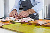 Crop anonymous male cook in apron putting bacon slices on colorful plate with cheese while preparing breakfast in kitchen