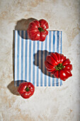 From above of ripe fresh red tomatoes placed on rough checkered tablecloth on plane table surface indoors