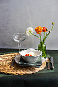 Gedeckter Tisch mit Hahnenfußblüten auf Betonhintergrund