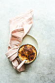 Top view of glass cup with coffee cream dessert with chocolate powder and ice served on plate with spoon on napkin for refreshing summer meal against blurred background