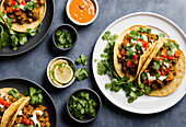 Ansicht von oben auf appetitliche mexikanische Tortilla-Tacos mit Fleisch und Kichererbsen, serviert mit Koriander und Limette auf schwarzem Hintergrund. Generative KI