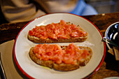 Appetizing crusty toasts with fresh tomato slices on ceramic plate in restaurant during breakfast