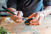 Anonymous male chef in apron using bar mixing spoon to dish black caviar from jar during serving meal in restaurant at Zermatt Switzerland