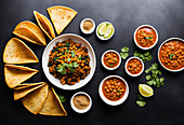 Top view of served tortilla taco shells and bowl of delicious meat and chickpeas for filling together with lime and seasoning on black background. Generative AI