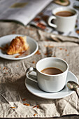 Cozy coffee break with a fresh croissant on a rustic table.