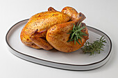 From above of whole Roasted Chicken ready to be served on a concrete plate plate on a white table