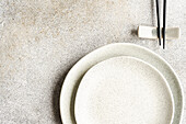 Minimalistic table setting with tableware and cutlery on concrete background