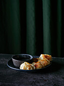 Yummy fried gyoza on plate with sauce in bowl placed against green curtains at table in restaurant