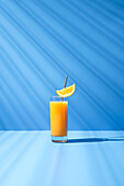 Squeezed orange juice garnished with orange slice on blue background