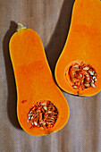 From above of juicy pumpkin split in half orange with seeds and flesh placed on table