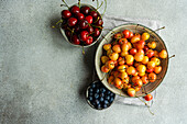 Bowl with organic ripe red and white sweet cherries and bowl with blueberry on the kitchen table