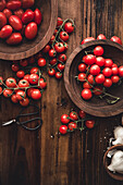 Top view of bunch with ripe red cherry tomatoes placed on wooden table in bowls