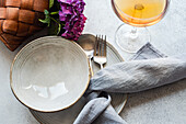 Top view of purple hydrangea placed on white table near ceramic plates and glass with drink