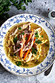 Warm bowl of chicken noodle soup with carrots and parsley, perfect for comfort food
