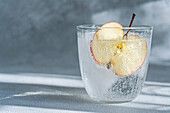 Eine Nahaufnahme eines Glases Tonic Water mit einer Apfelscheibe, die die Bläschen und das erfrischende Aussehen des Getränks hervorhebt