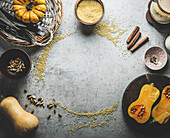 Pumpkin cooking background frame with millet , cinnamon sticks, cardamom and kitchen utensils. Top view