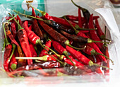 High angle closeup of a plastic bag filled with an abundance of dried red chilies