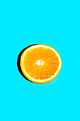 Closeup of slice of fresh orange fruit isolated on blue background with copy space