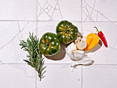 Flacher Teller mit frischem Gemüse auf gefliestem Hintergrund. Kochen gesundes Mittagessen mit verschiedenen Tomaten und Kräutern