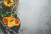 Healthy seasonal food background with pumpkins, fresh herbs and cutlery on rustic background, top view. Border