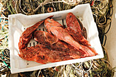 Frischer, ungekochter Wolfsbarsch in einem weißen Behälter unter Sonnenlicht in Soller während der traditionellen Fischfangzeit
