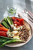 Ein nahrhaftes Frühstückskonzept, das eine ausgewogene Mahlzeit mit frischem Gemüse, cremigem Feta, proteinreichem Buchweizen und mit Pesto belegten Spiegeleiern präsentiert