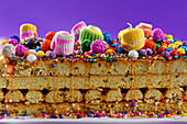Cross sectional view of Peruvian nougat with glaze and colorful sprinkles placed over purple background