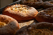 Fokussiert leckeres gebackenes Brot mit Käse auf einem Aluminiumtablett in einer Bäckerei