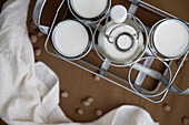 Top view of home made organic horchata drink served in transparent glasses and bottle placed on wooden table near napkin in a rustic kitchen