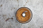 Top view of blender with crushed biscuits placed on marble counter during pastry cooking