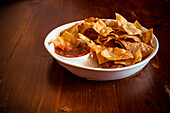 Mexikanische Mais-Chips mit Salsa-Sauce auf Holztisch