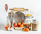 Baking setting with apricots, kitchen utensils, tools, honey and ingredients at white background. Baking with seasonal fruit at home. Front view.