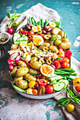 Top view of delicious assorted Nicoise salad with fresh vegetables placed in tray on table