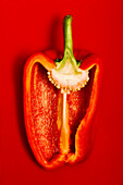 Top view of appetizing fresh sliced red pepper on red surface