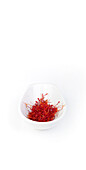 Nahaufnahme einer weißen Schale, gefüllt mit leuchtend roten Safranfäden, vor einem sauberen weißen Hintergrund, der die reiche Farbe und Textur des Gewürzes betont