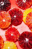 Blick von oben auf den Hintergrund von bunten, frischen, saftigen Grapefruit- und Orangenscheiben, die in Wasser für die Zubereitung von Shots und Cocktails eingelegt sind