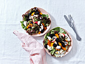 Top view with two plates of salad with roasted squash, berries and goat cheese. Vegetarian festive dinner.