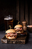 Delicious hamburgers with pulled pork and coleslaw salad in crispy buns served on rustic wooden board