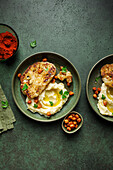 Top view of delicious roasted cauliflower with mashed potatoes and spiced harissa chickpeas served on ceramic plate on green table background