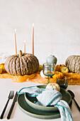 Burning candles in sticks and assorted pumpkins arrange on white table during Halloween celebration