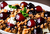 Appetizing sweet creamy dessert with cherries and crumbs served with mint leaves in white bowl